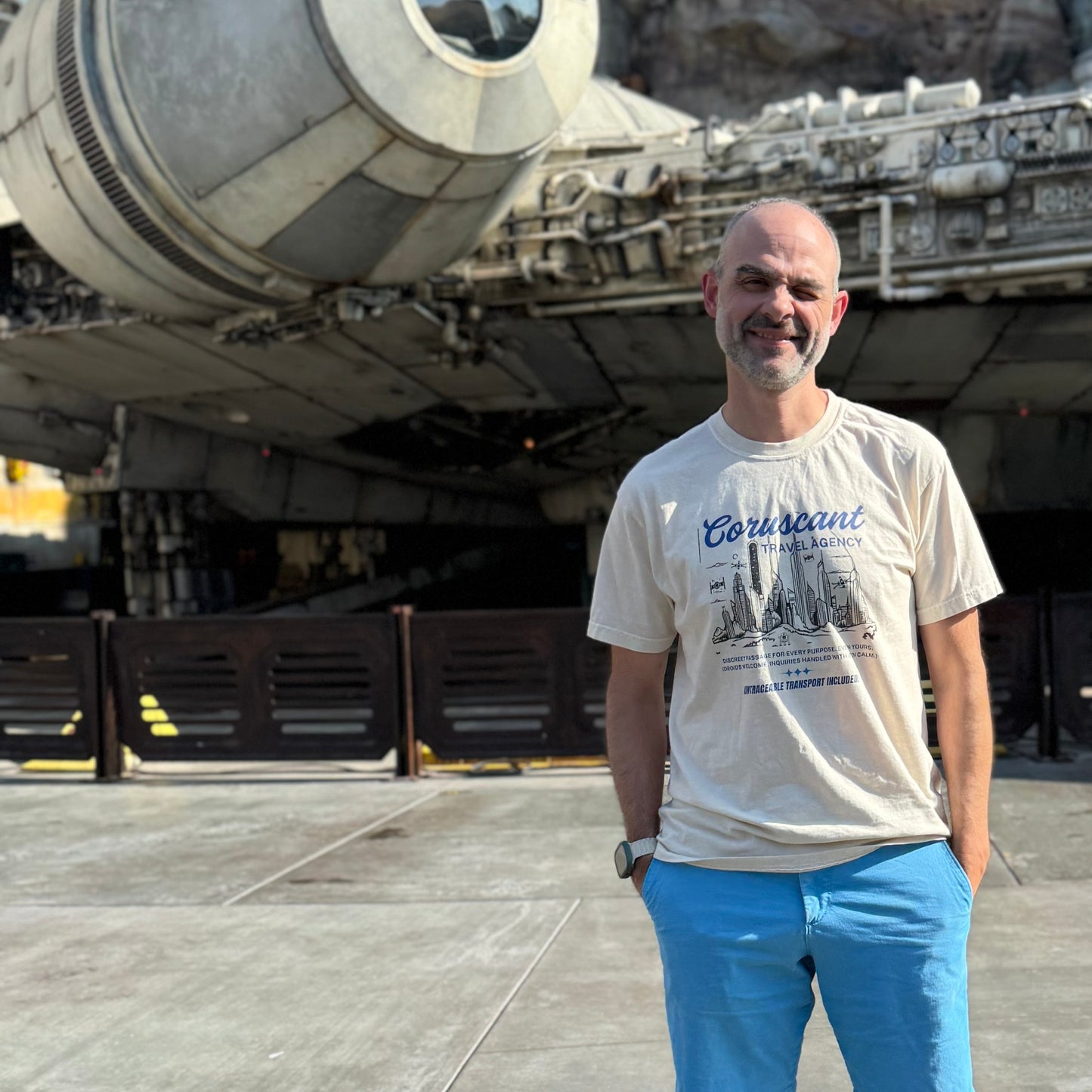 man standing in front of galaxy's edge ride at disneyland with coruscant travel agency tshirt