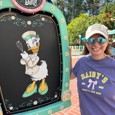 Daisy Duck's Bow Shop Disney Tee purple with yellow lettering and pink bow