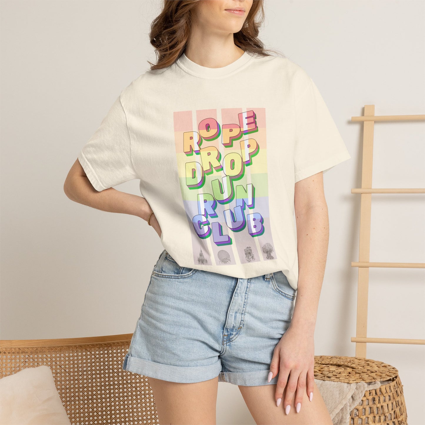 Person wearing a pride cream t-shirt with colorful text design and denim shorts in a casual setting.
