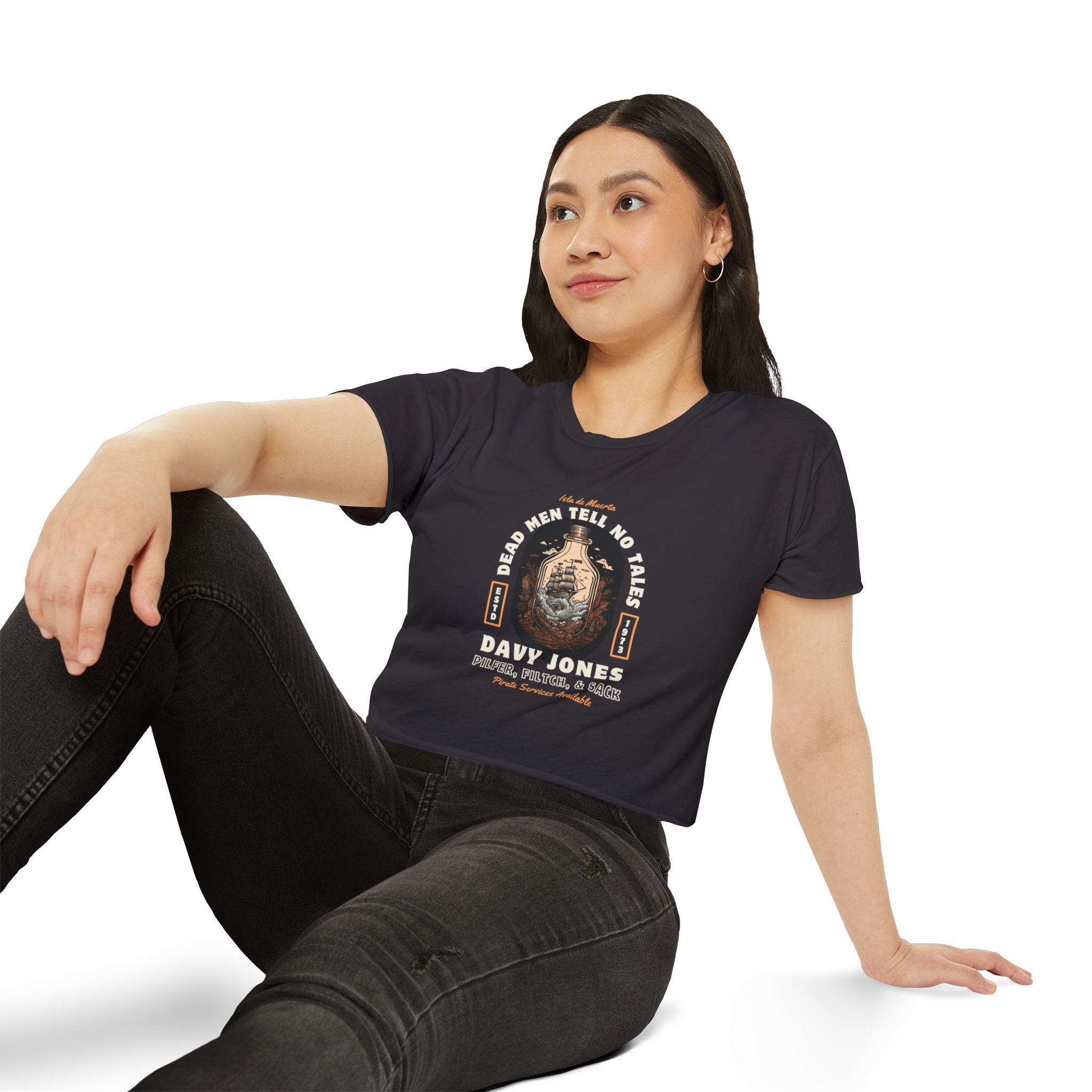 Woman wearing a black t-shirt with a pirates of the Caribbean graphic design sitting on a white background