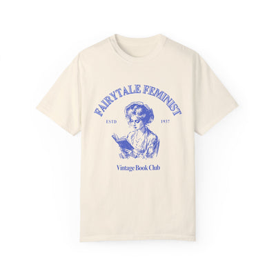 Beige t-shirt with blue graphic and text 'FAIRYTALE FEMINIST Vintage Book Club' on a white background