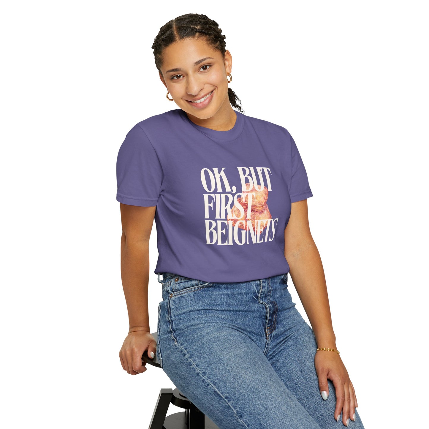 Person wearing a purple t-shirt with text and sitting on a stool against a white background