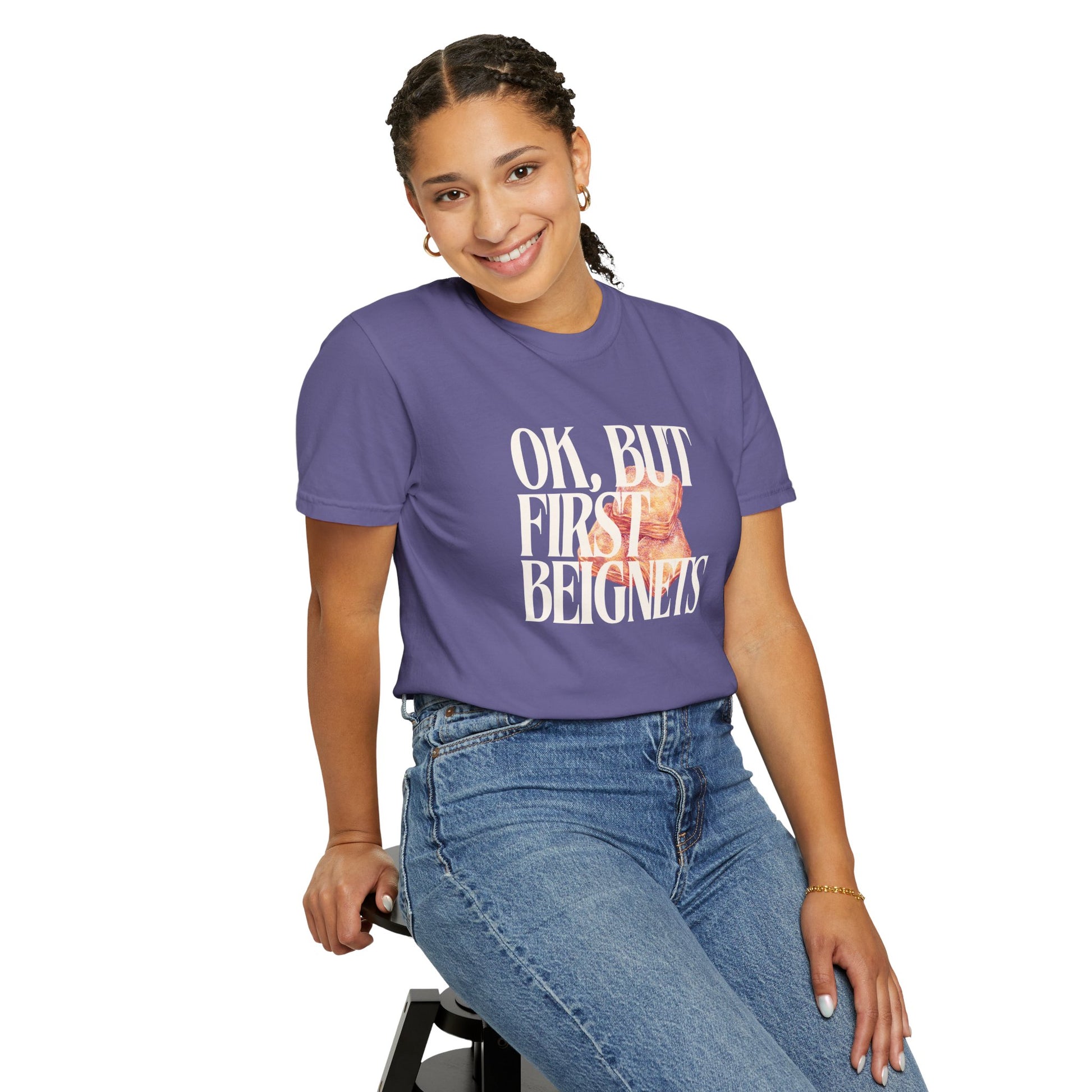 Person wearing a purple t-shirt with text and sitting on a stool against a white background