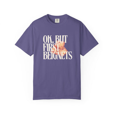 Purple t-shirt with 'OK, BUT FIRST BEIGNETS' text and beignet graphic on a white background