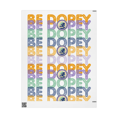 A vertical poster print featuring the word 'BE DOPEY' repeated in multiple pastel colors with a circular medallion containing a figure, alongside the phrase 'BE DOPEY' in matching lettering on a white background.