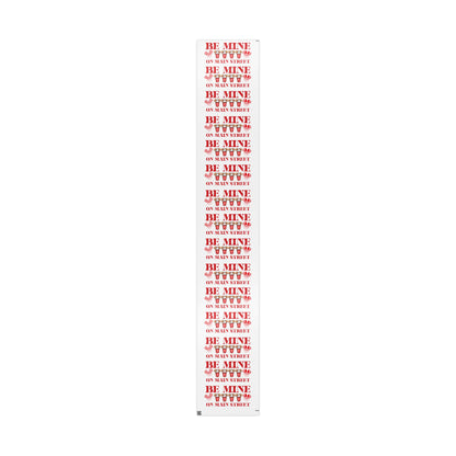Roll of red and white paper with 'Be Mine' text on a white background