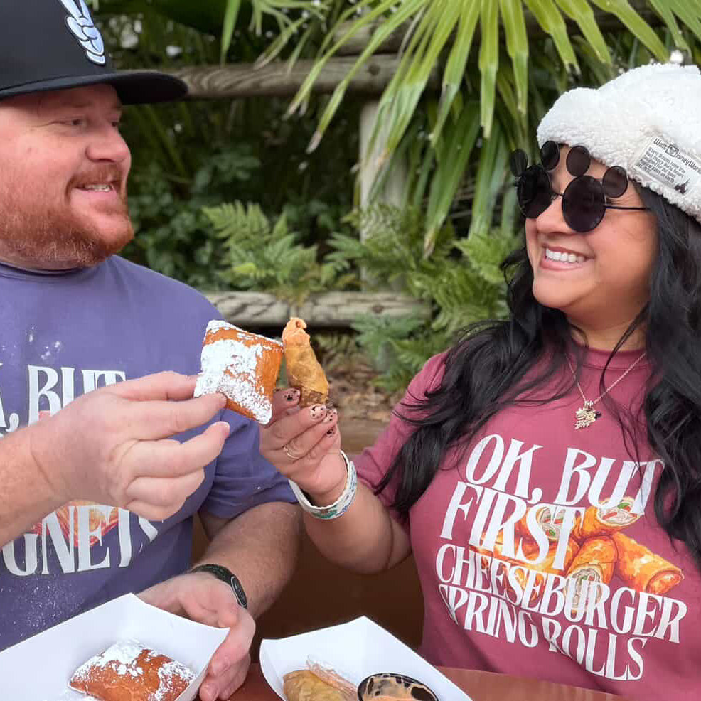 Two people enjoying food outdoors, wearing matching t-shirts with a cheeseburger graphic.