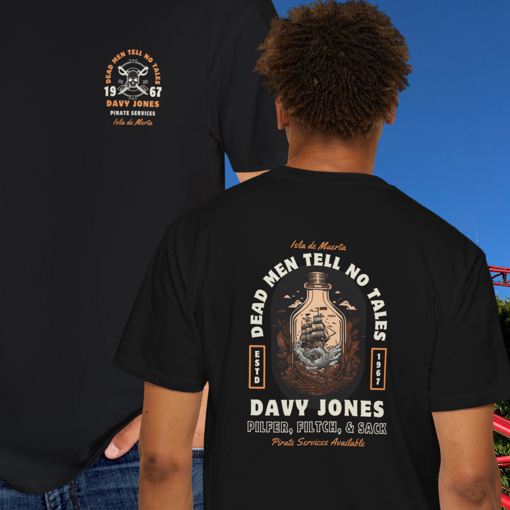 Person wearing a black t-shirt with a pirate-themed design on the back, set against a blue sky.