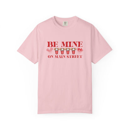 Pink t-shirt with 'Be Mine on Main Street' text and graphics on a white background