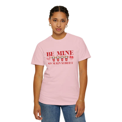 Person wearing a pink t-shirt with 'Be Mine on Main Street' text and candy corn graphics.