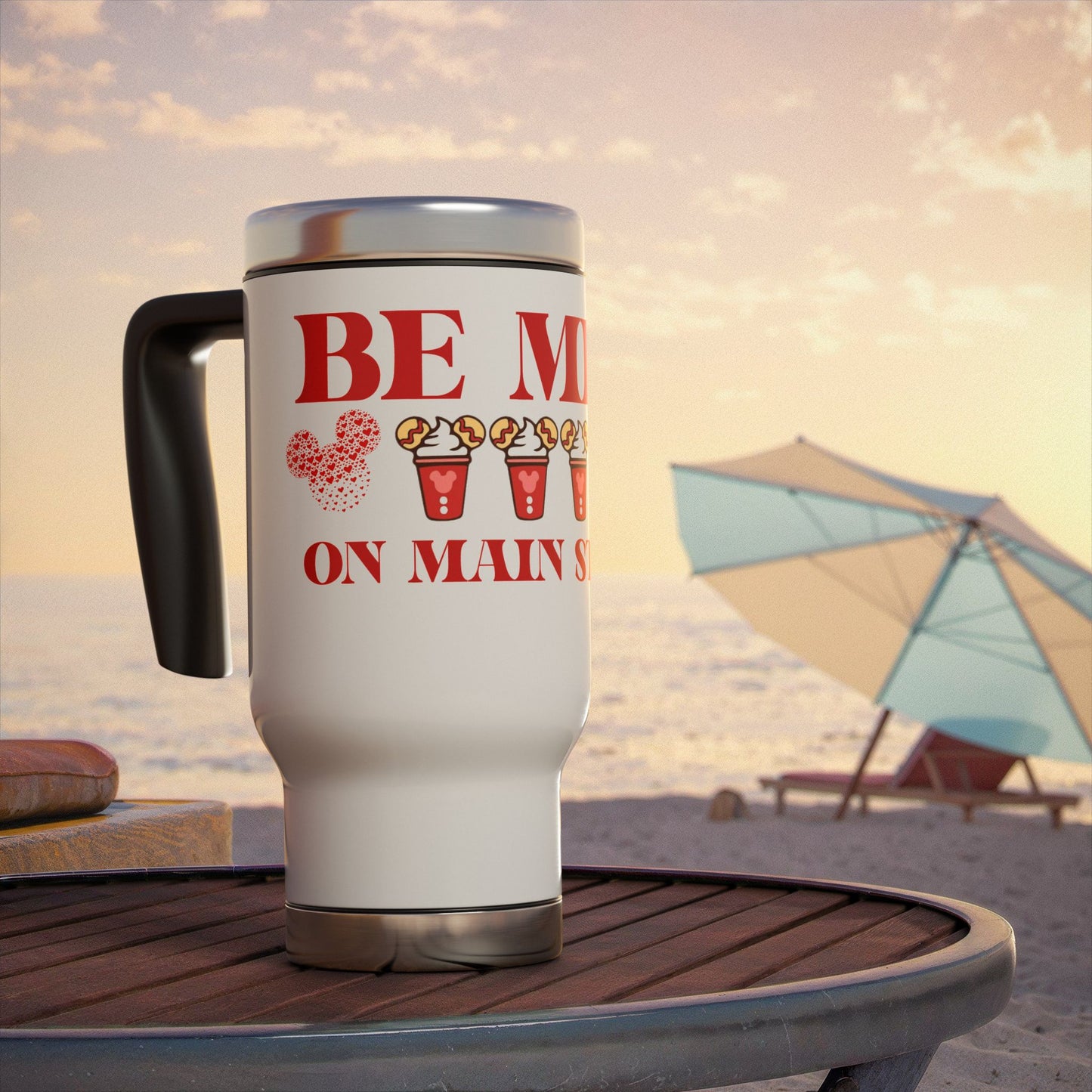 Travel mug with 'Be Mine on Main Street' text on a beach setting with disney icons
