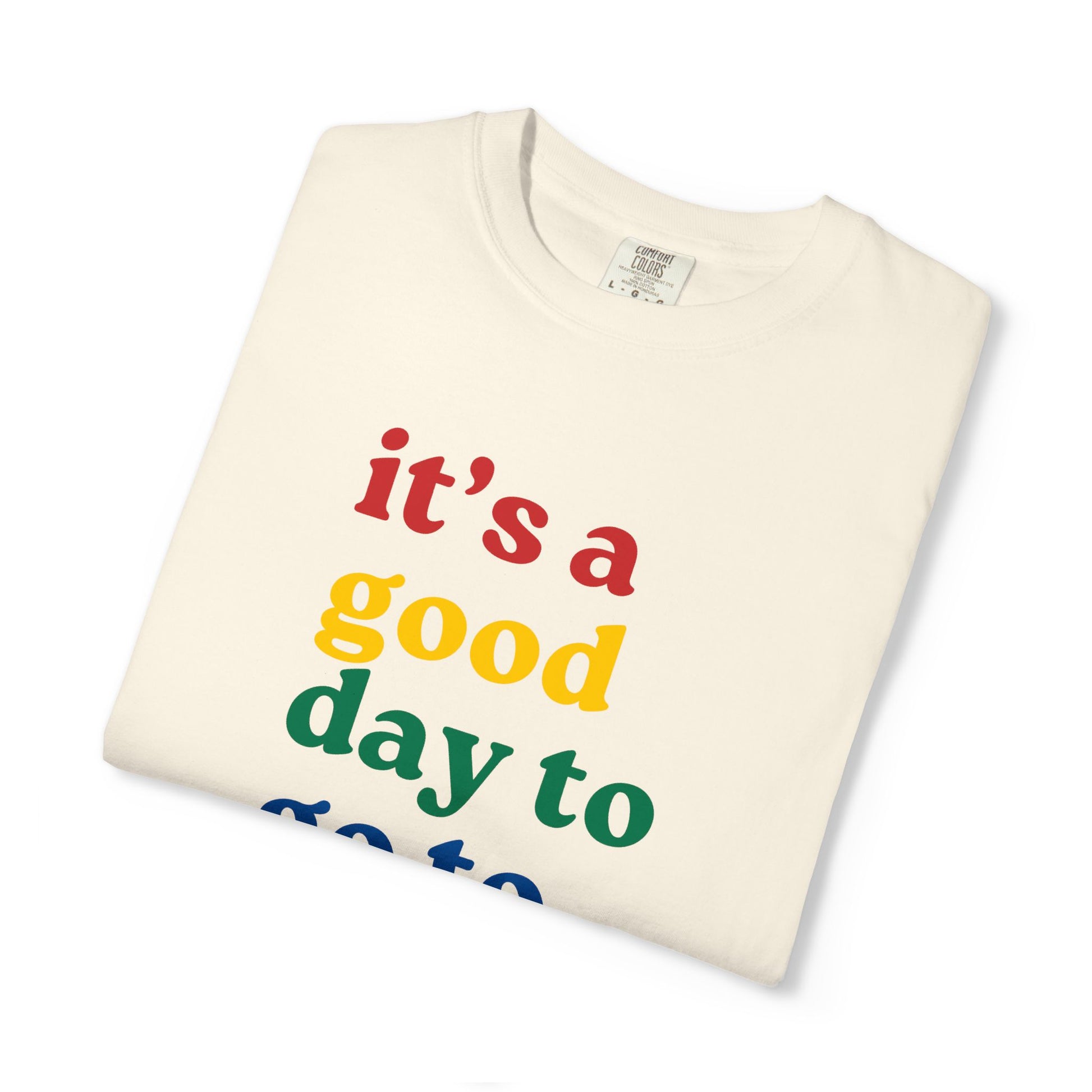 Folded t-shirt with colorful text 'it's a good day to' on a white background