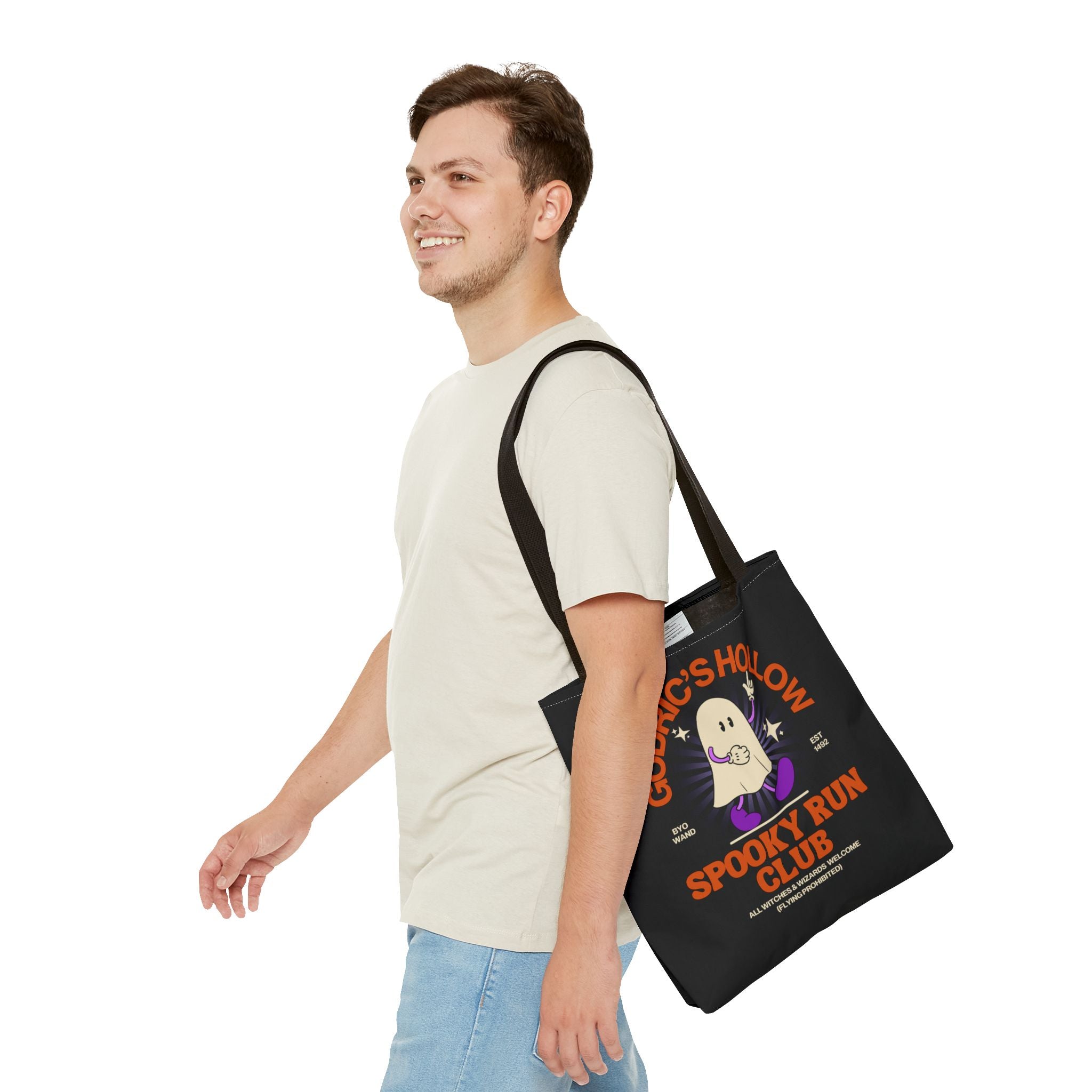 Man carrying a black tote bag with a 'Spooky Run Club' design on a white background