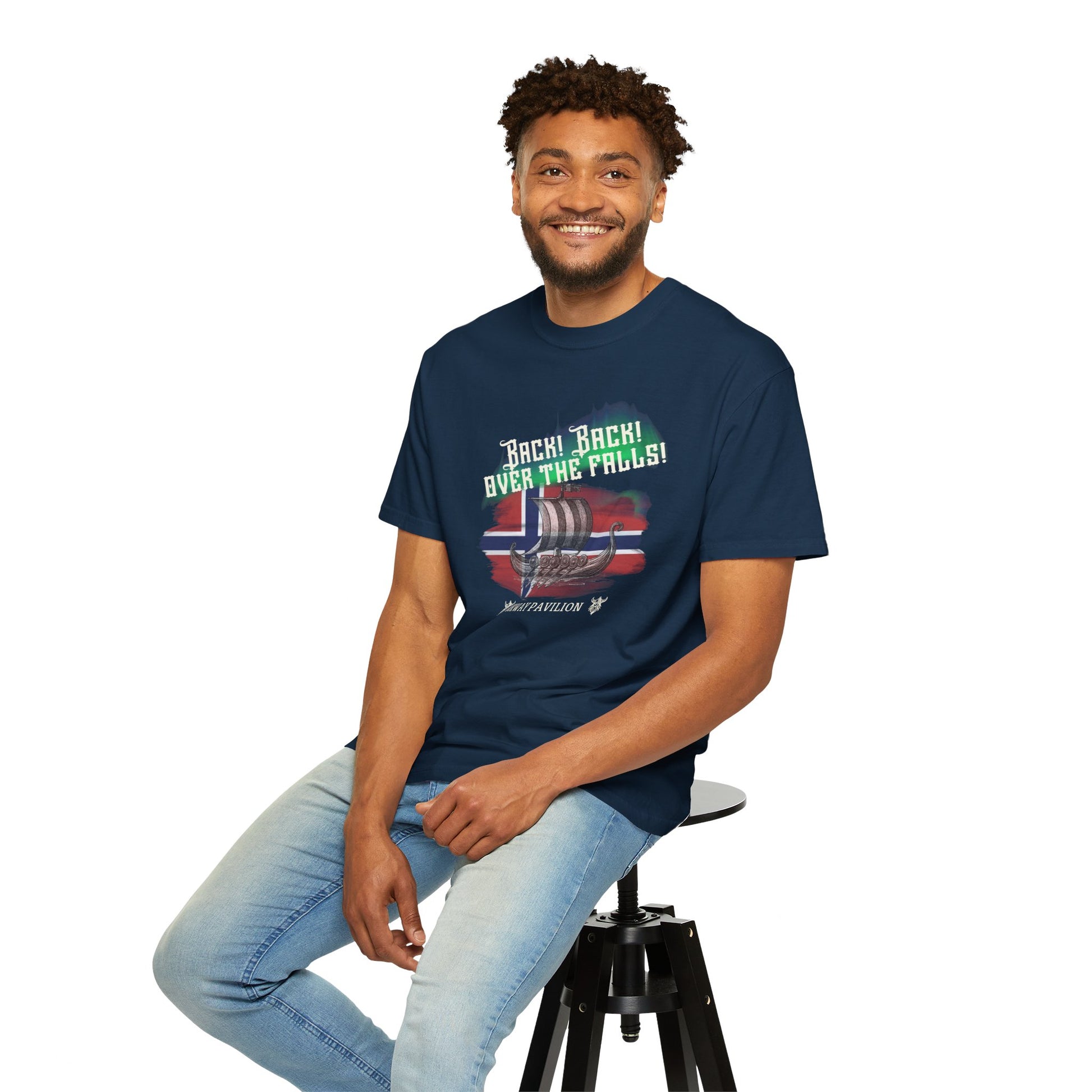 Man wearing a navy blue t-shirt with a graphic design, sitting on a stool against a white background