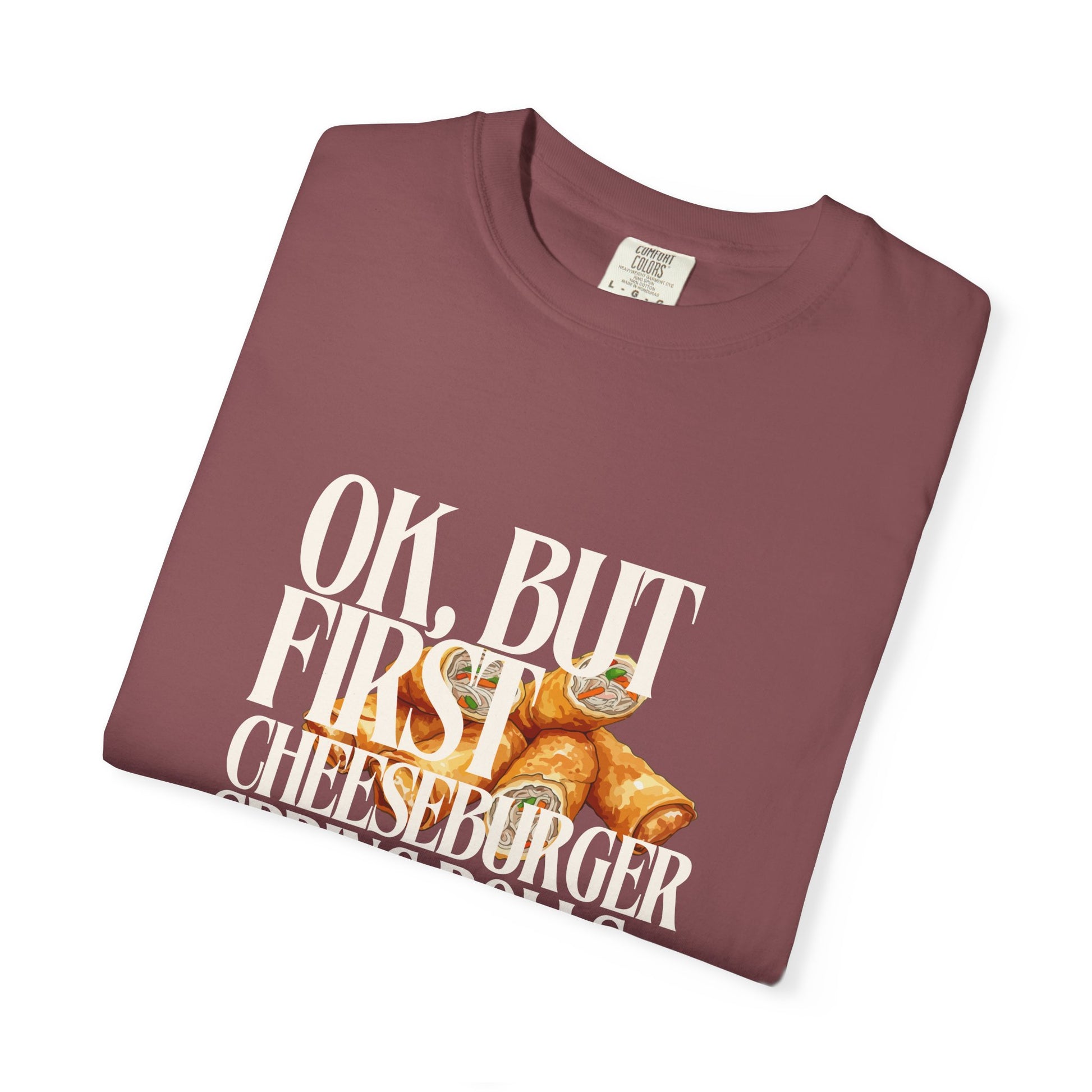 Folded maroon t-shirt with cheeseburger graphic and text on a white background