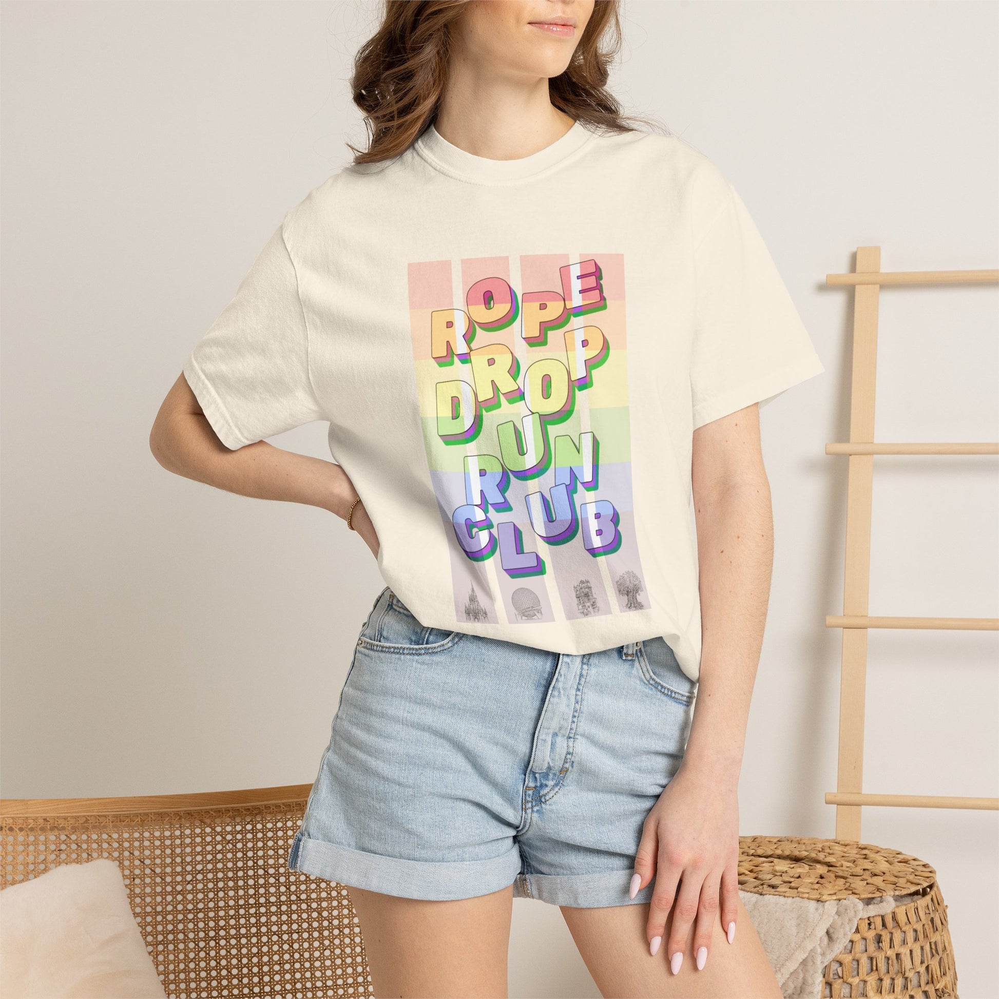 Person wearing a pride cream t-shirt with colorful text design and denim shorts in a casual setting.